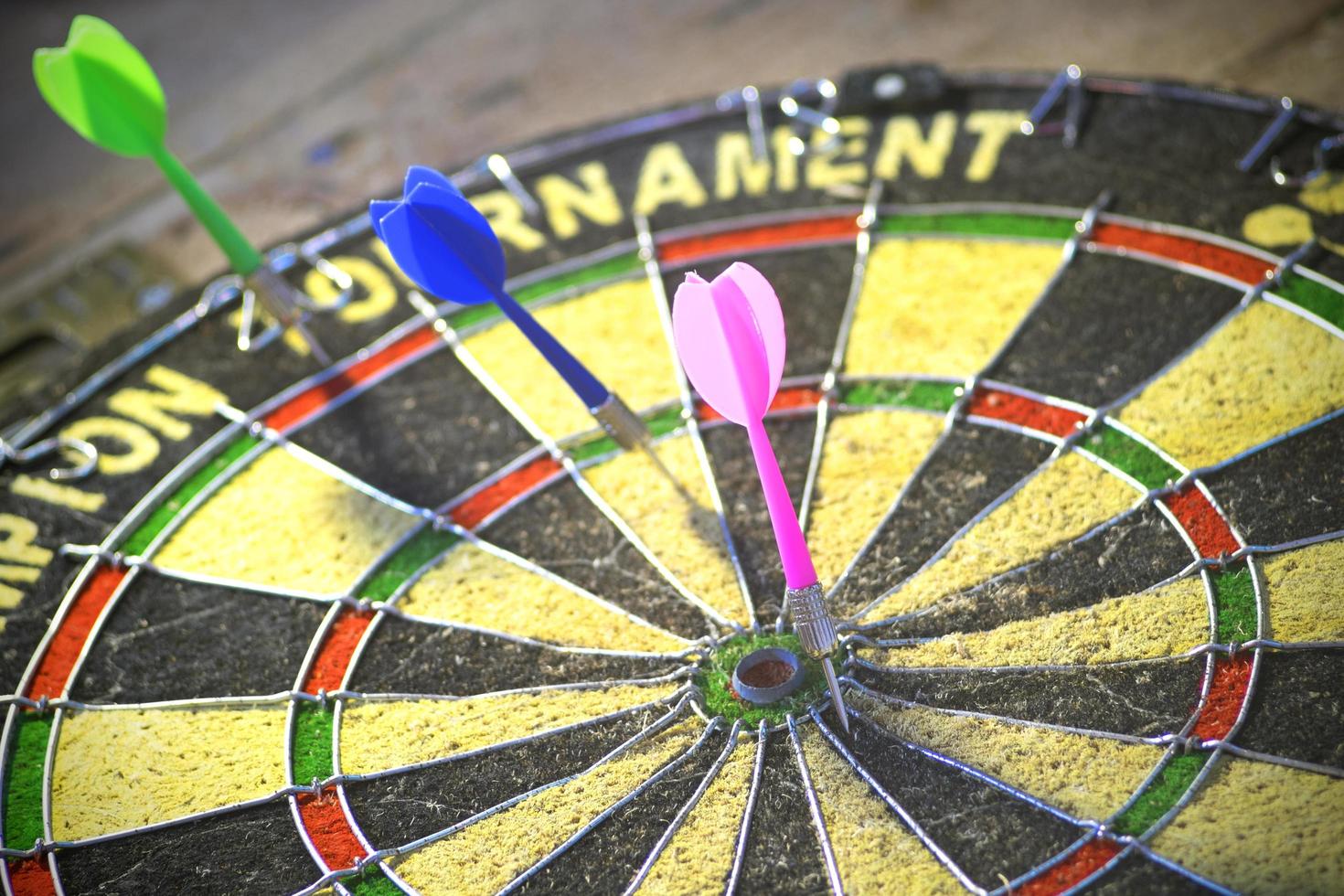 A dart board in black and yellow with colorful arrows. photo