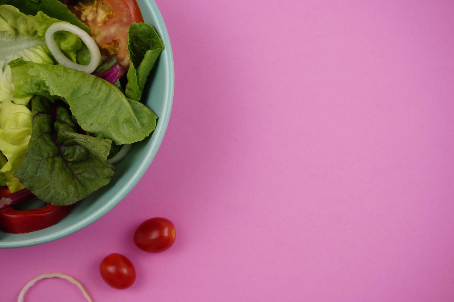 Ensalada de verduras sobre fondo rosa con espacio. foto