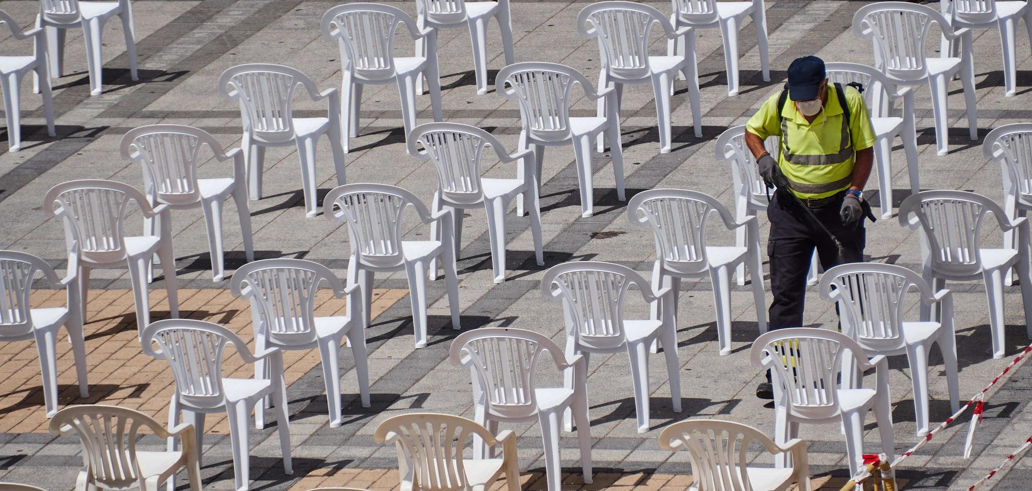 Spain, Aug 2020 - Man sanitizing chairs photo