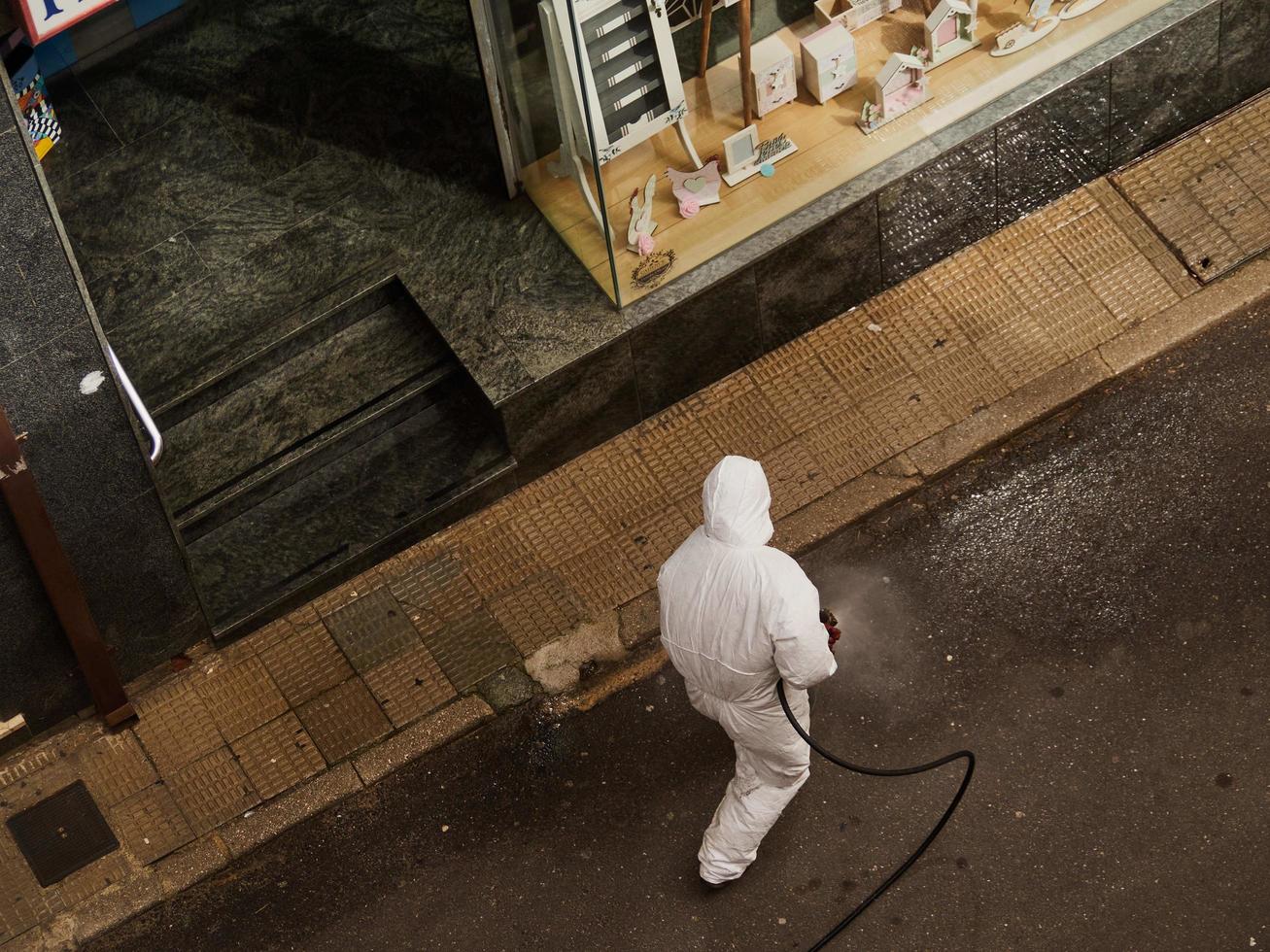 Spain, Mar 2020 - Man sanitizing a sidewalk photo