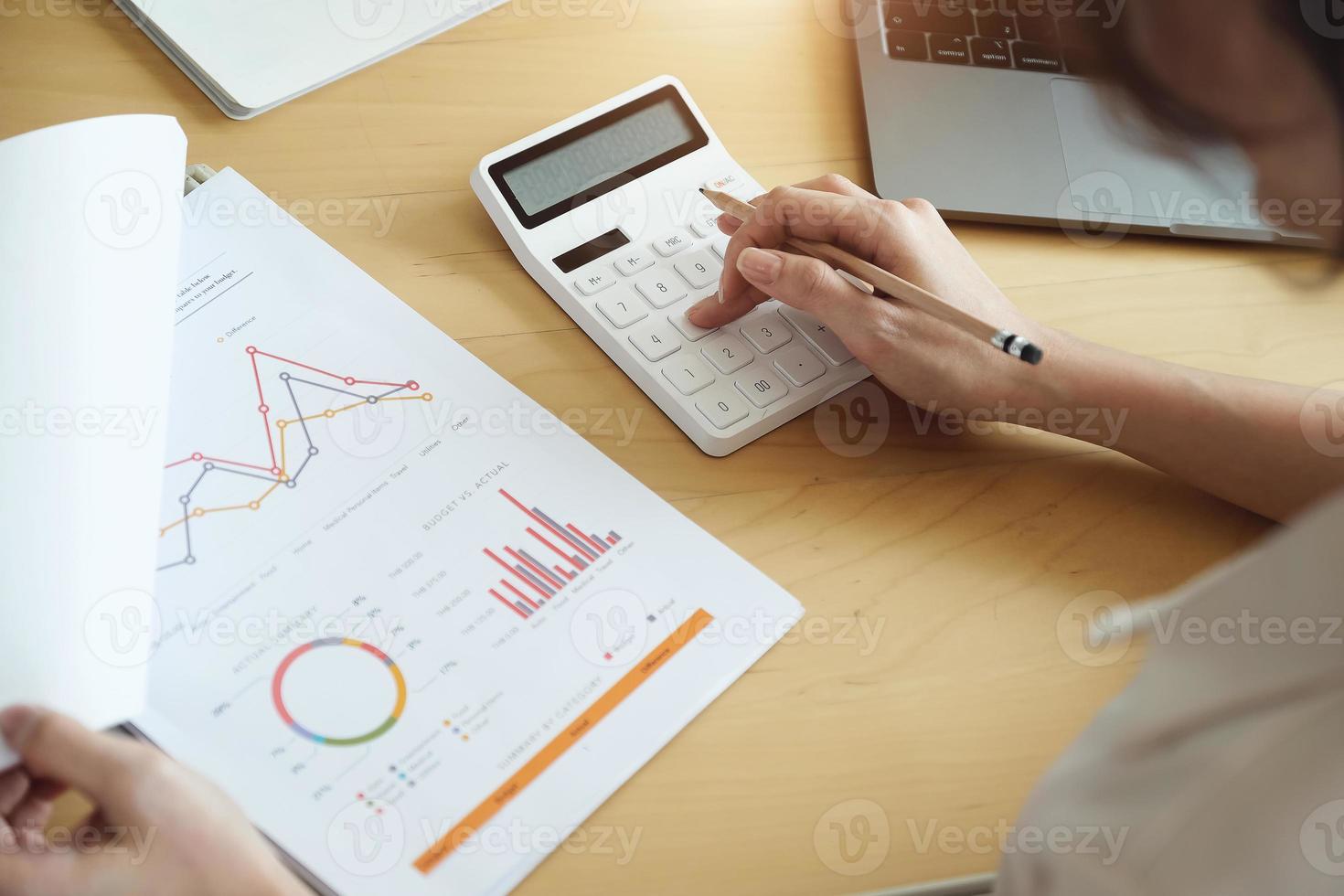 Woman checking documents with calculator photo