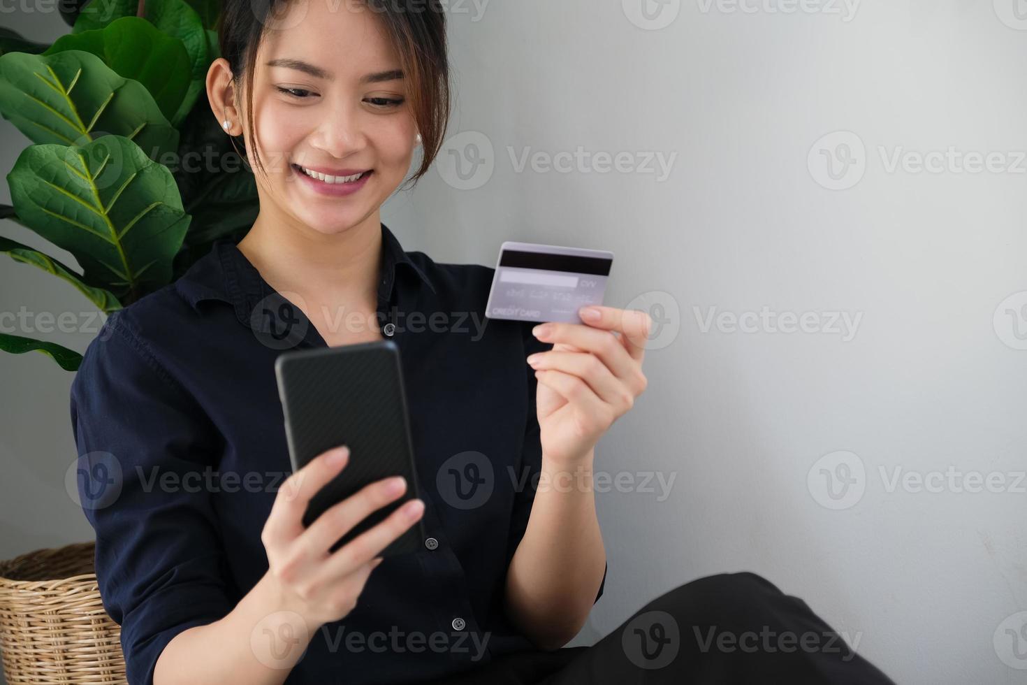 Mujer pagando en su teléfono inteligente sosteniendo una tarjeta de crédito foto