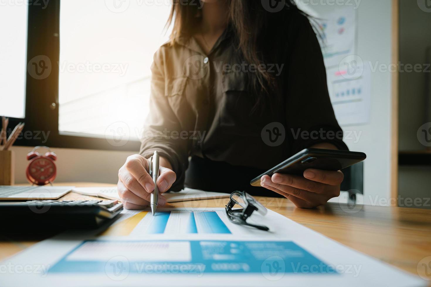 Close up of businesswoman's hand holding a pencil and financial paperwork with financial network diagram. photo