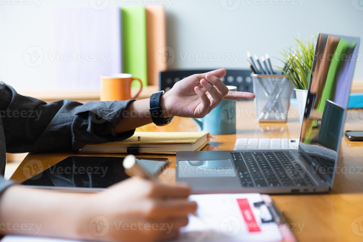 Cerrar la mano de la empresaria apuntando y analizando gráficos con una computadora portátil foto