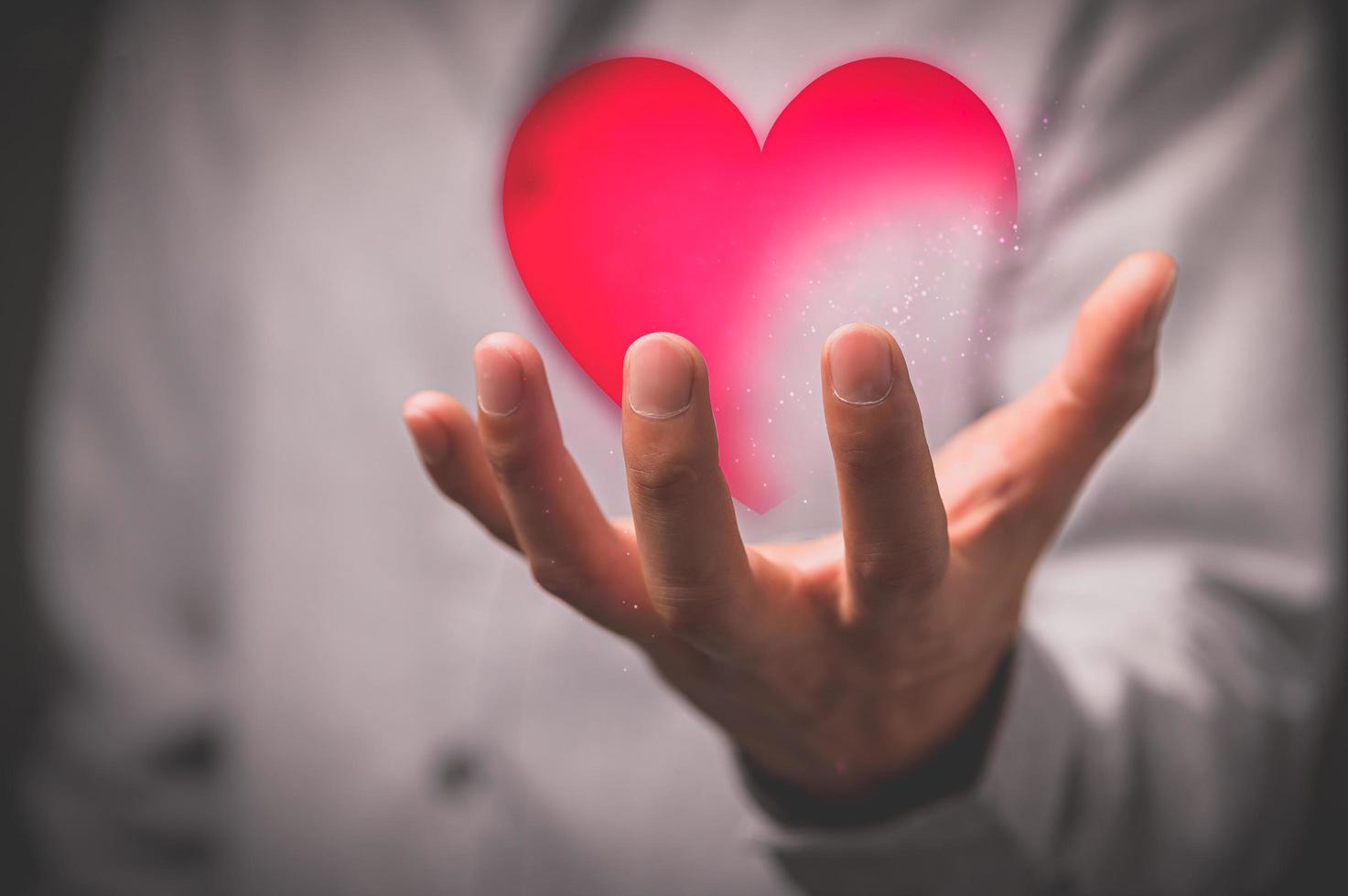 mano que muestra el símbolo del corazón holograma foto