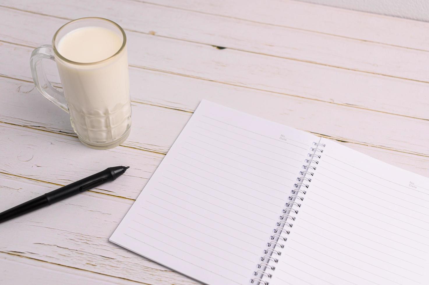 The notebook and a glass of milk are on the desk photo