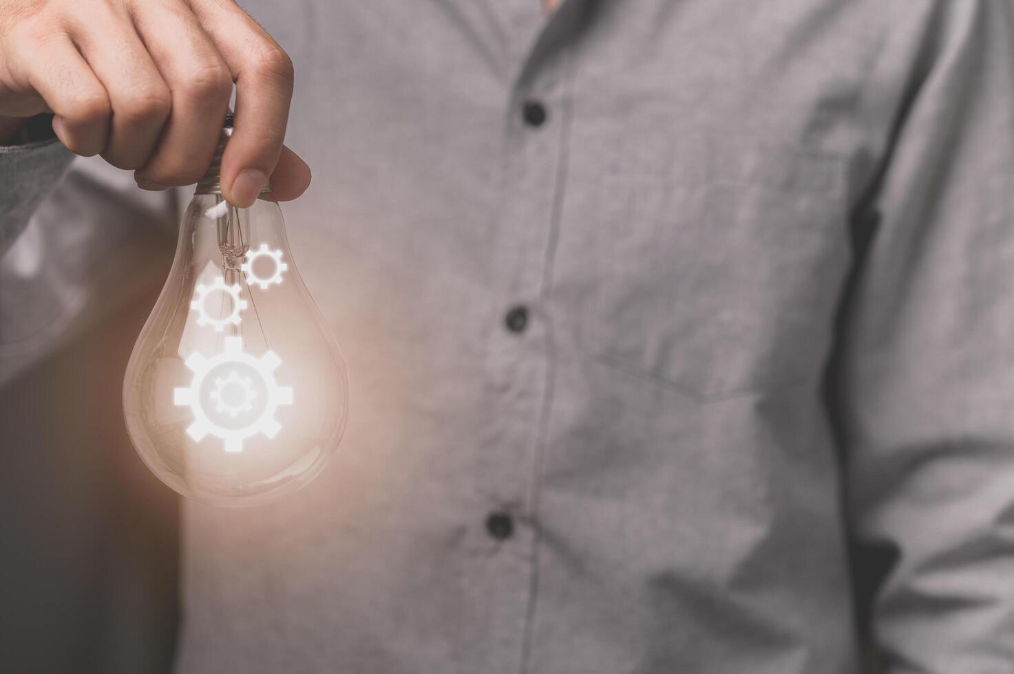 A business man's hand holds a light bulb with a gear icon photo