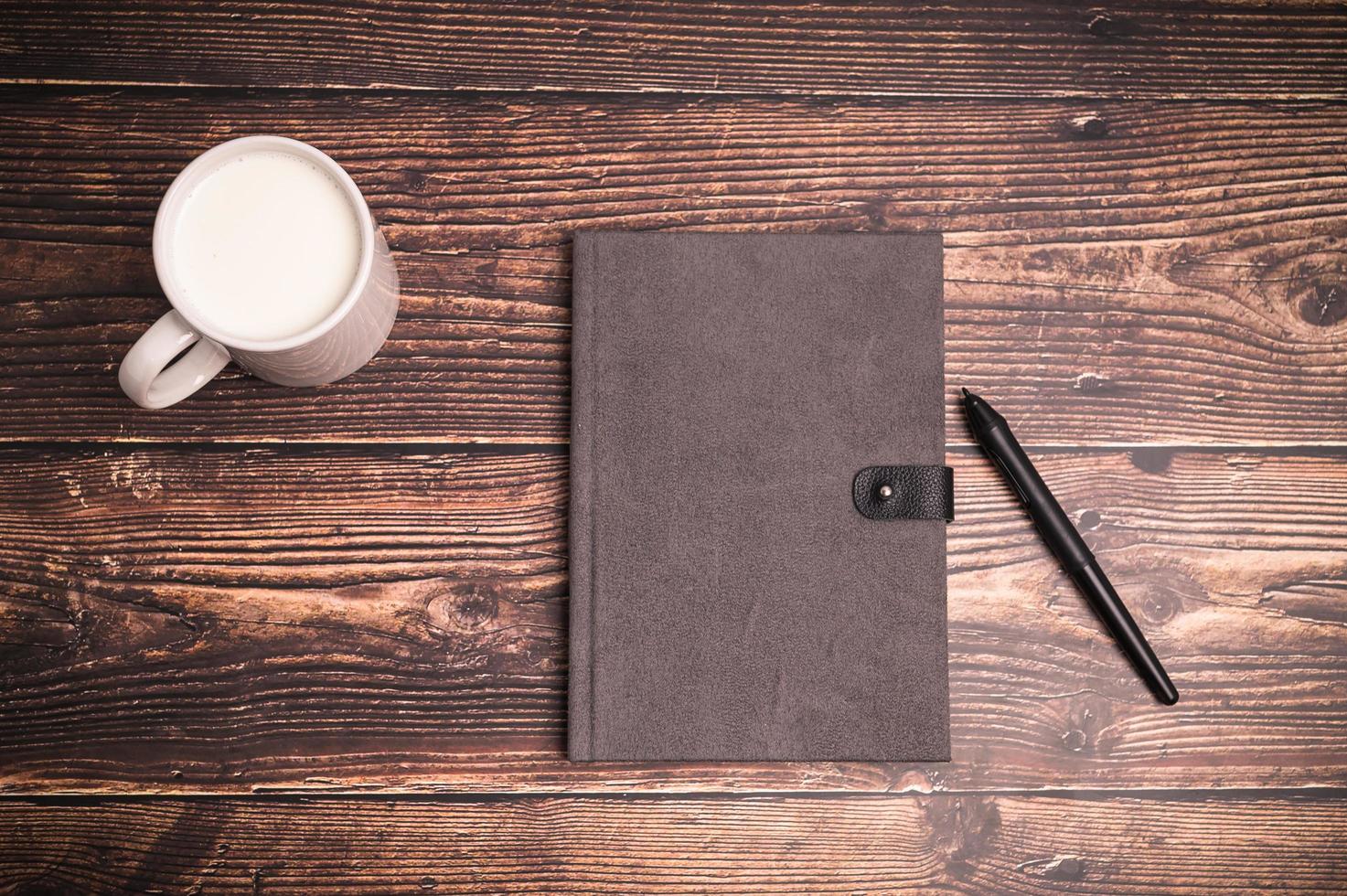 Notebook and a glass of milk on the desk photo