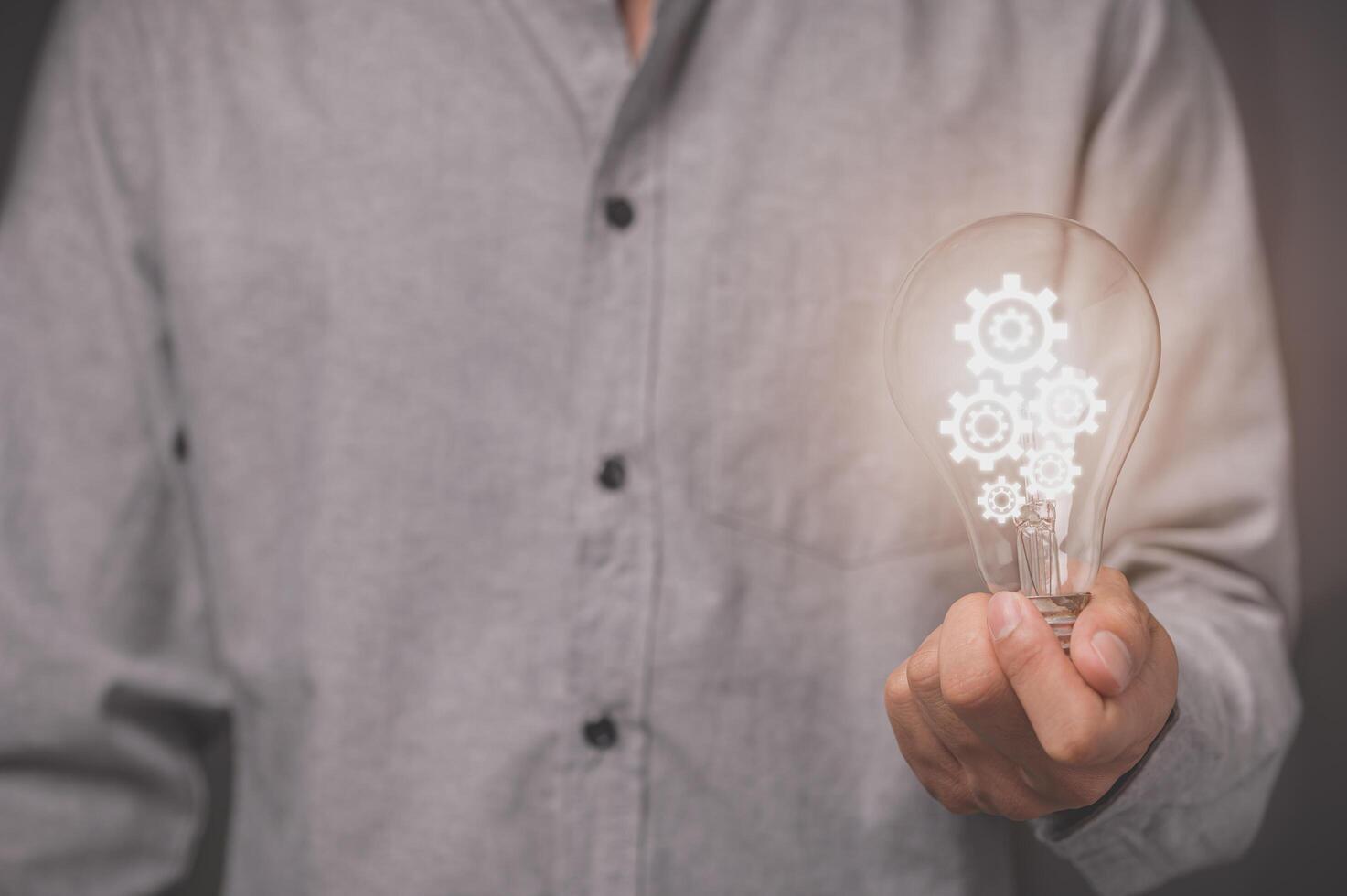 A business man's hand holds a light bulb and has a gear icon photo