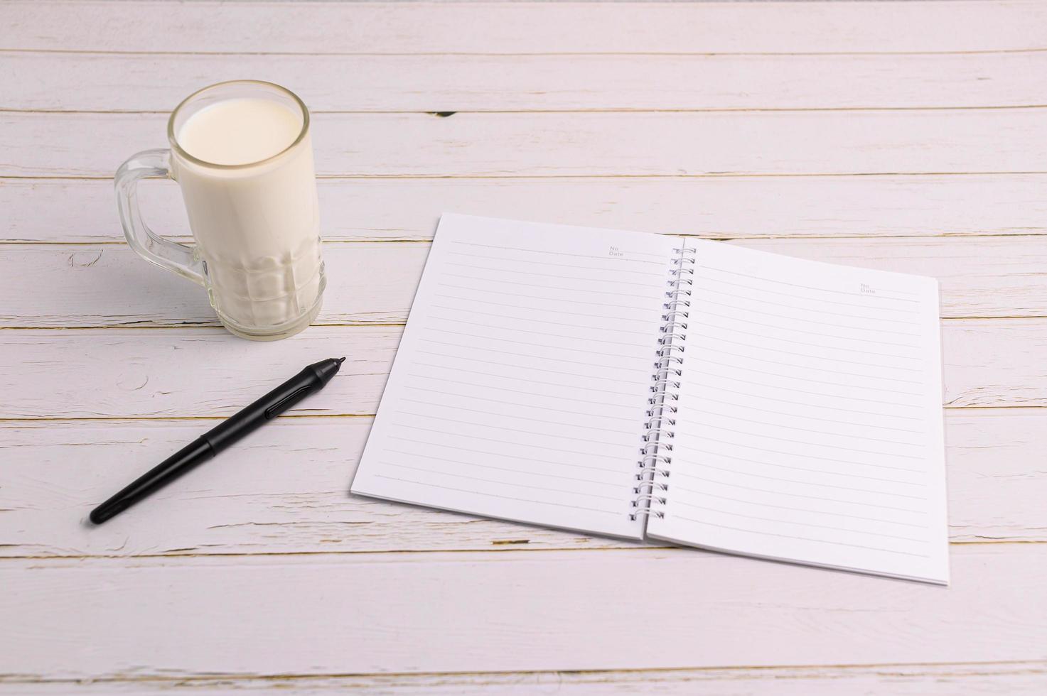 cuaderno y un vaso de leche en el escritorio. foto