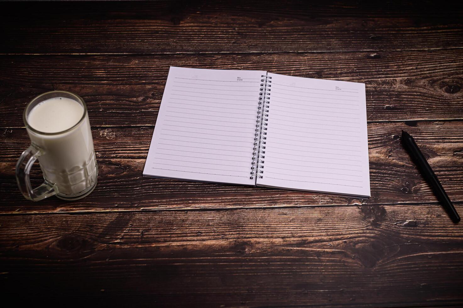 cuaderno y un vaso de leche en el escritorio. foto