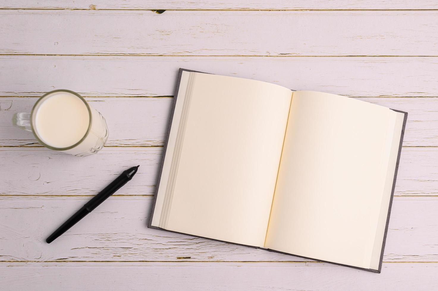 Notebook and a glass of milk on the desk photo