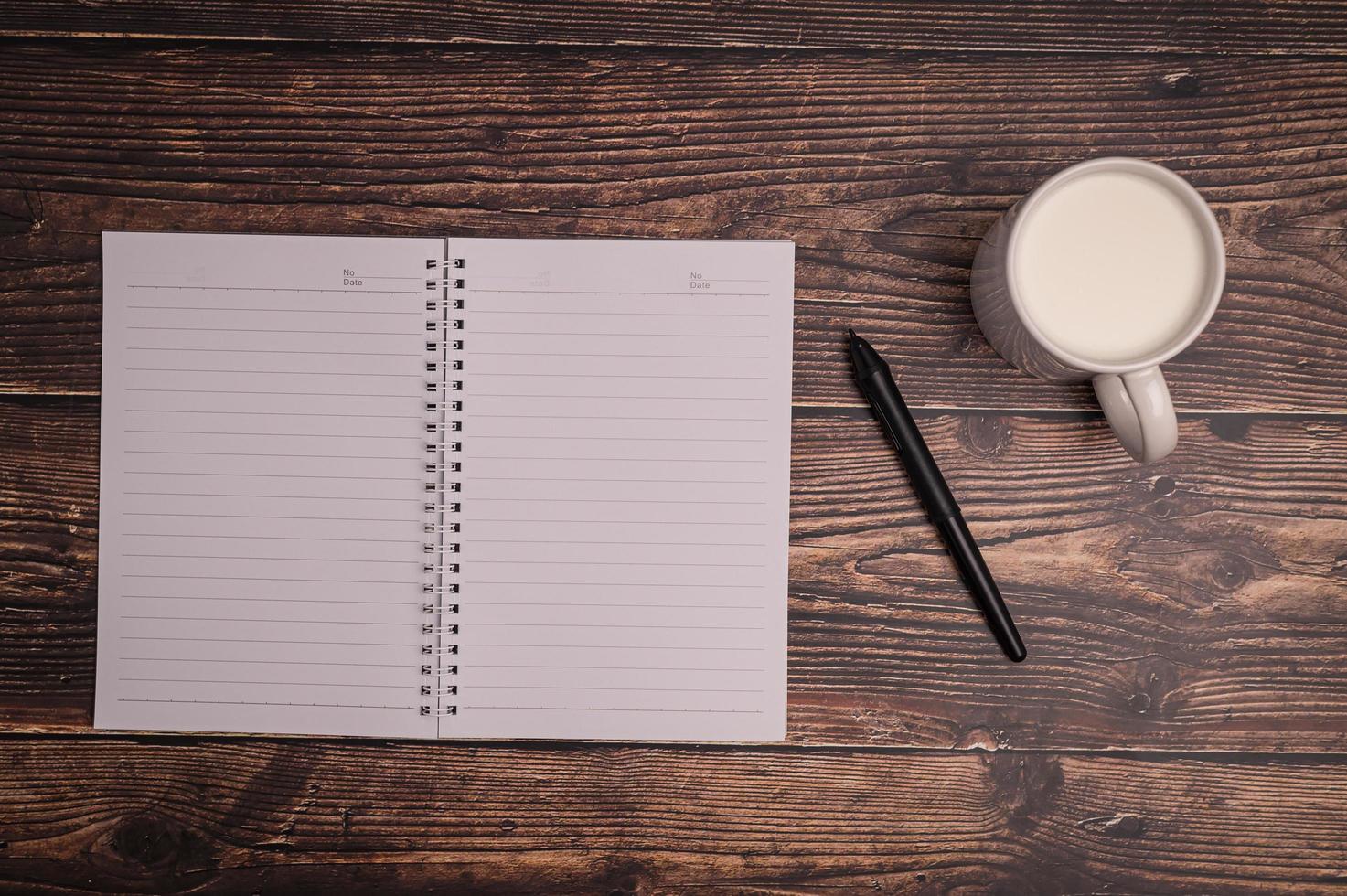 cuaderno y un vaso de leche en el escritorio. foto
