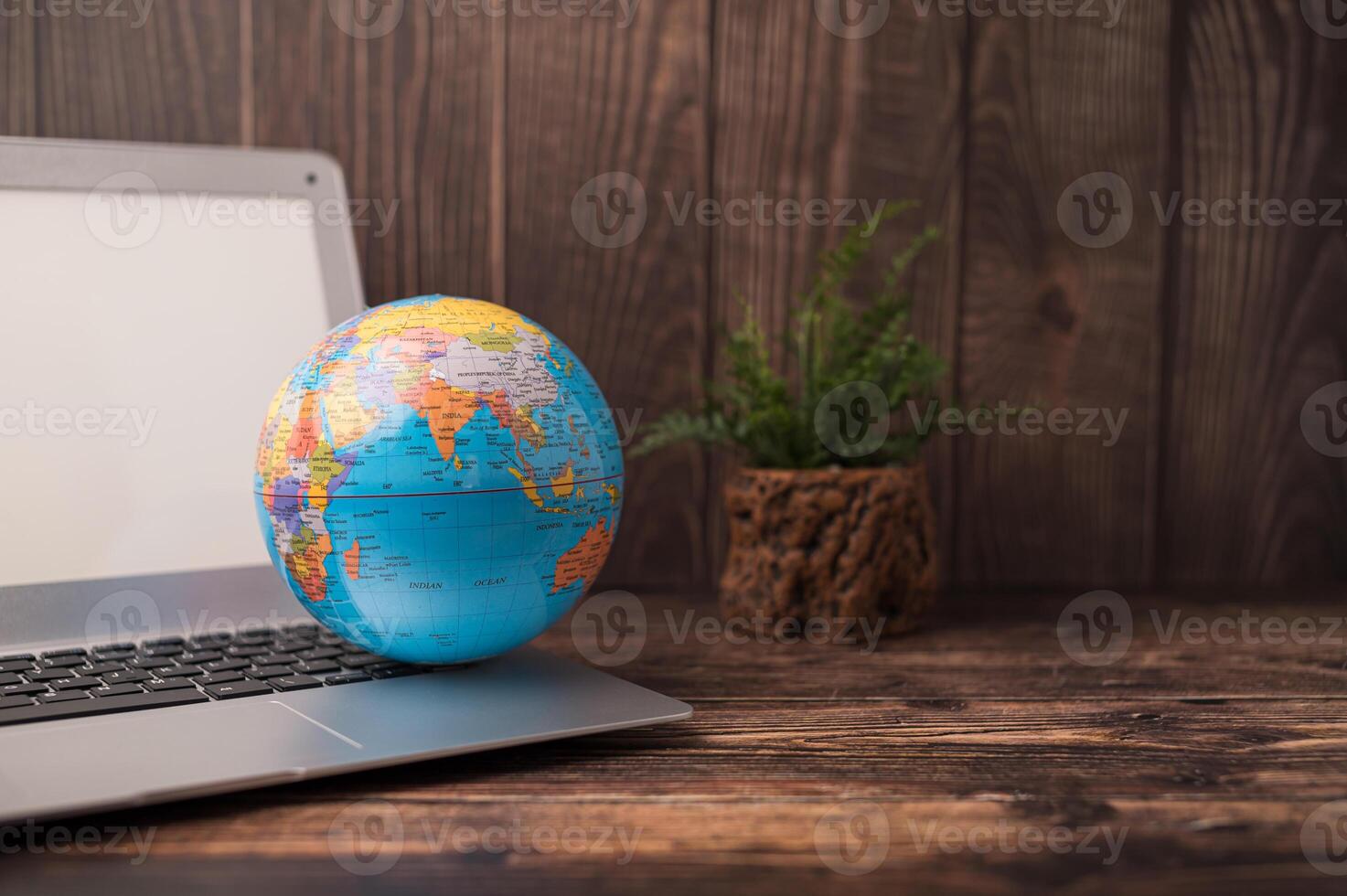 World globe on laptop on wooden table photo