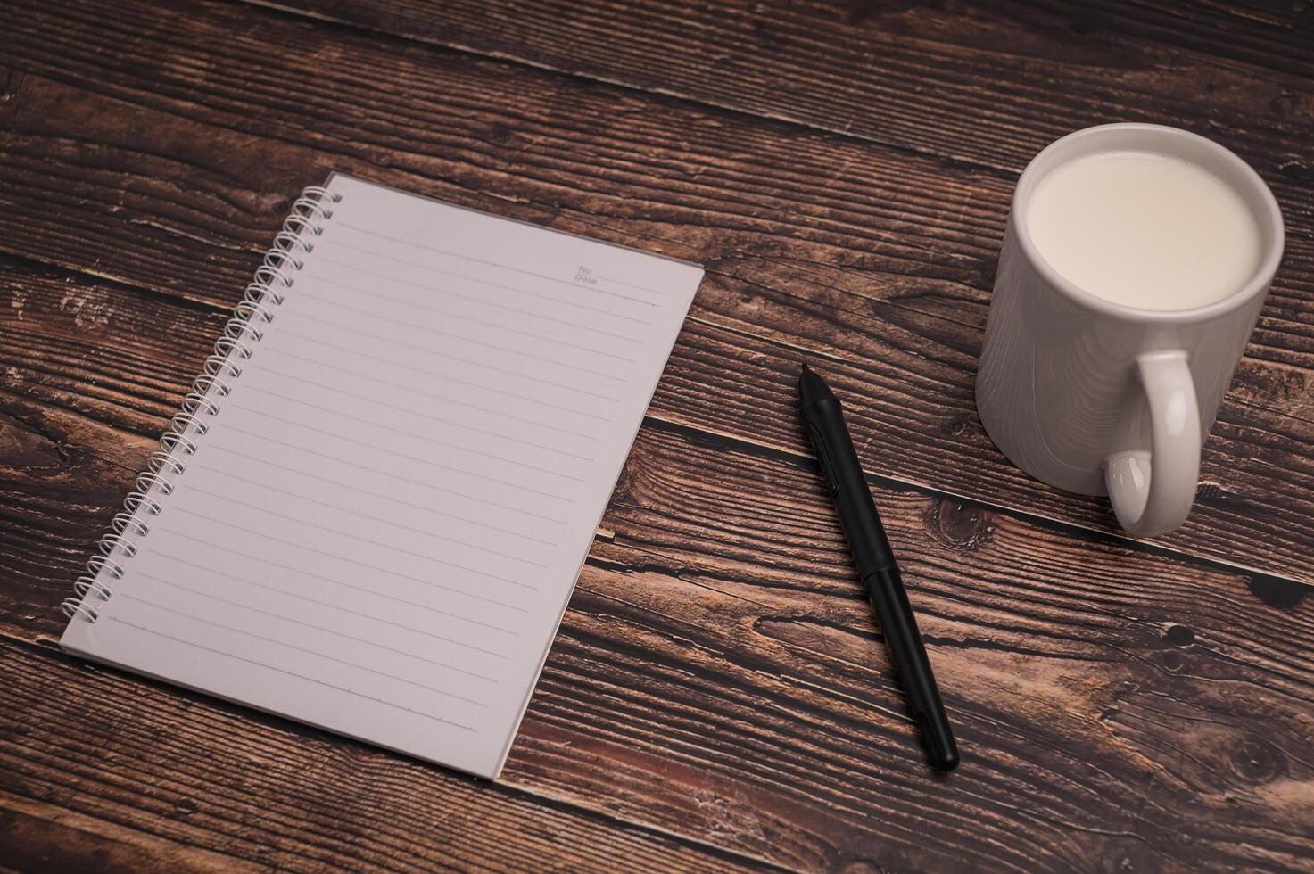 cuaderno y un vaso de leche en el escritorio. foto