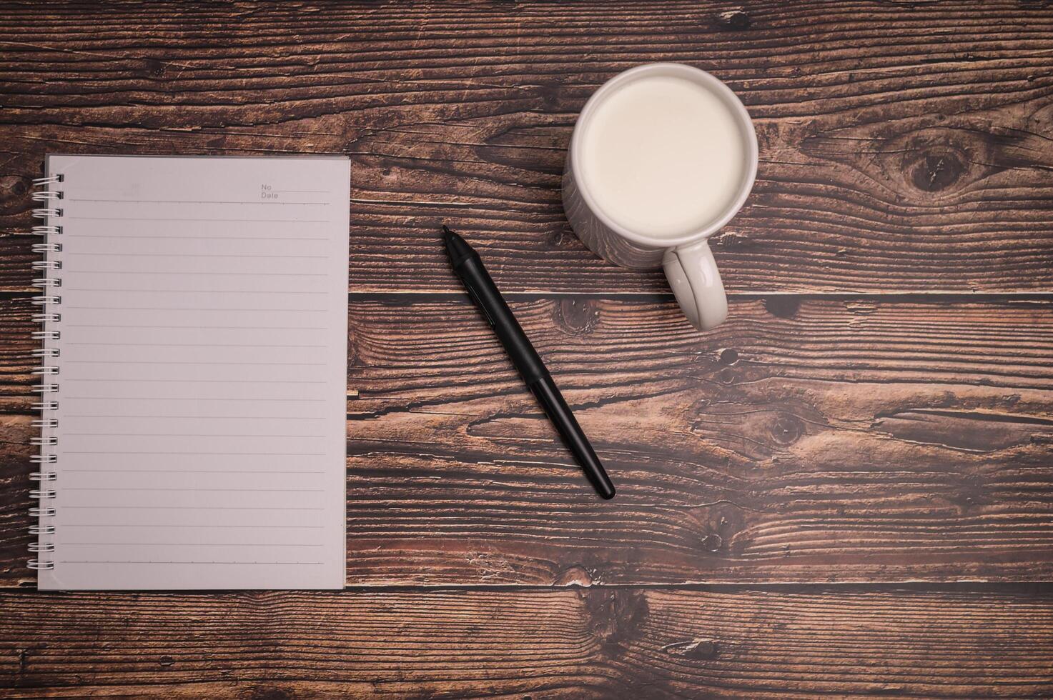 Notebook and a glass of milk on the desk photo