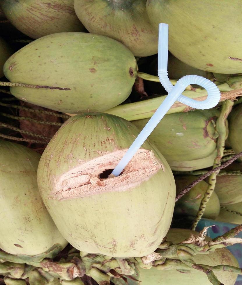 Sweet green coconut water with drinking straw photo