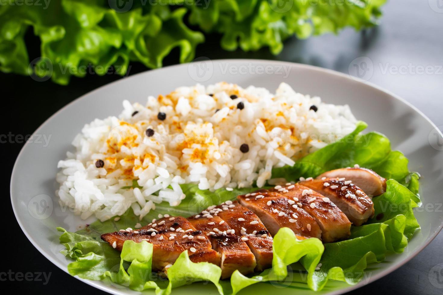 Comida casera - pollo teriyaki con arroz blanco y pimienta sobre un fondo negro foto