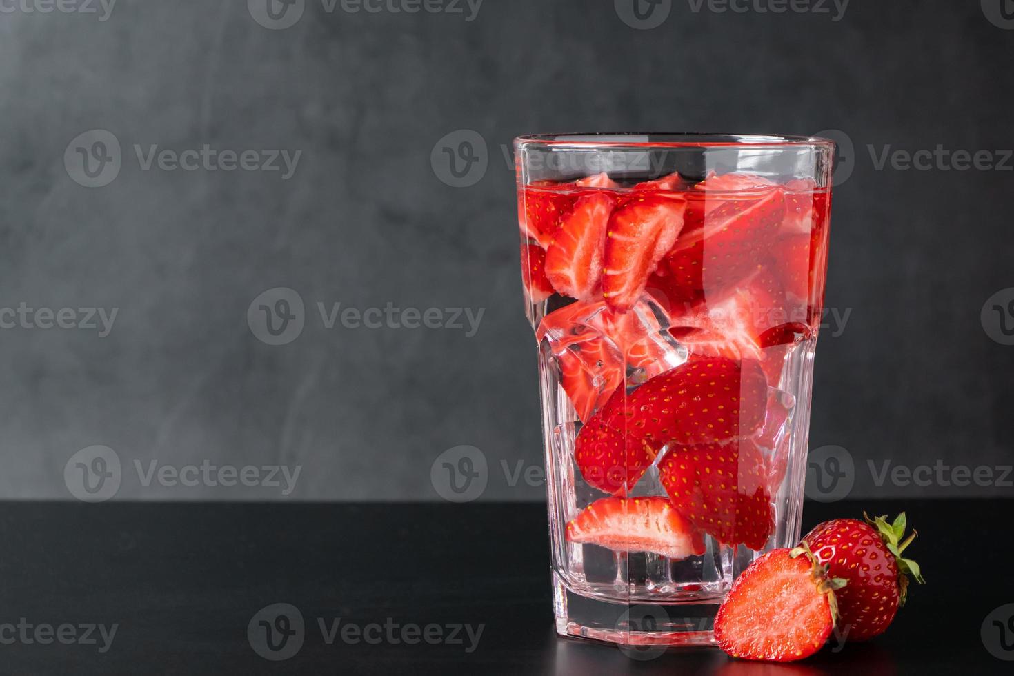 Bebida de hielo con fresas sobre fondo negro foto