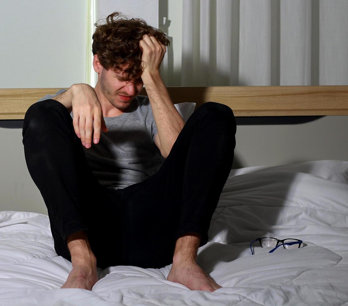 El hombre se sienta en el dormitorio estresado debido al desempleo foto