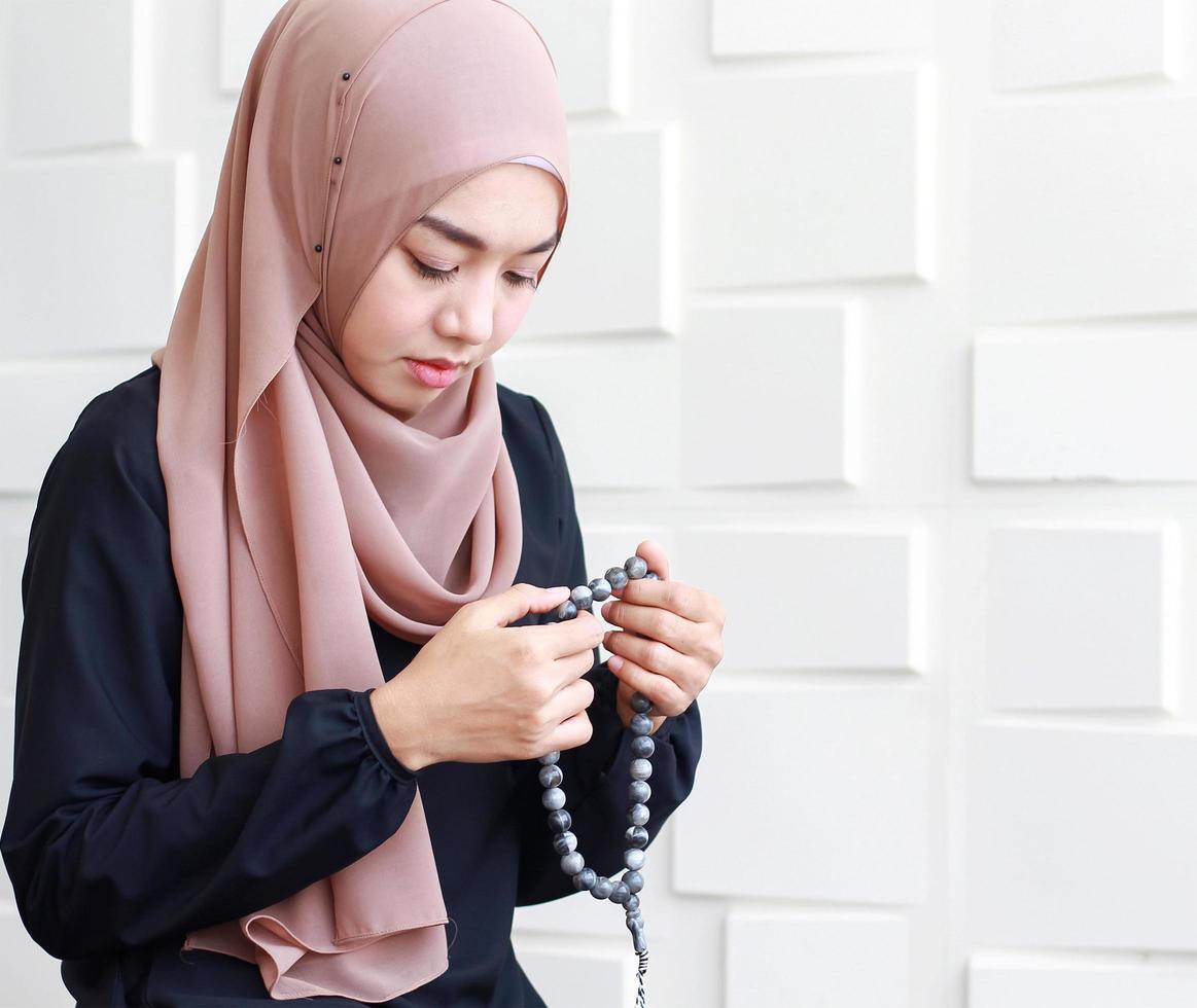 Retrato de mujer musulmana en traje tradicional con hijab y rosario rezando en una mezquita foto