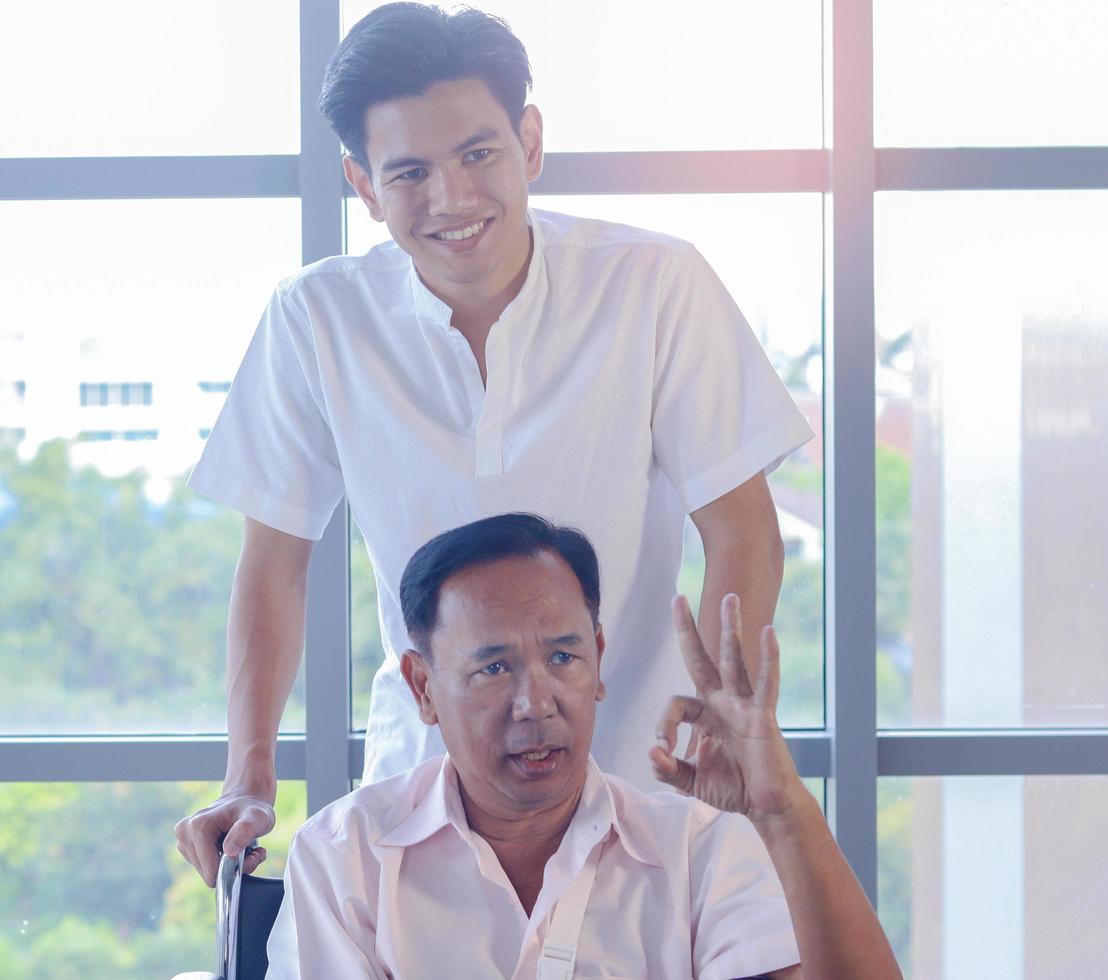 Son who cares for his father, who is a patient, while sitting in a wheelchair photo