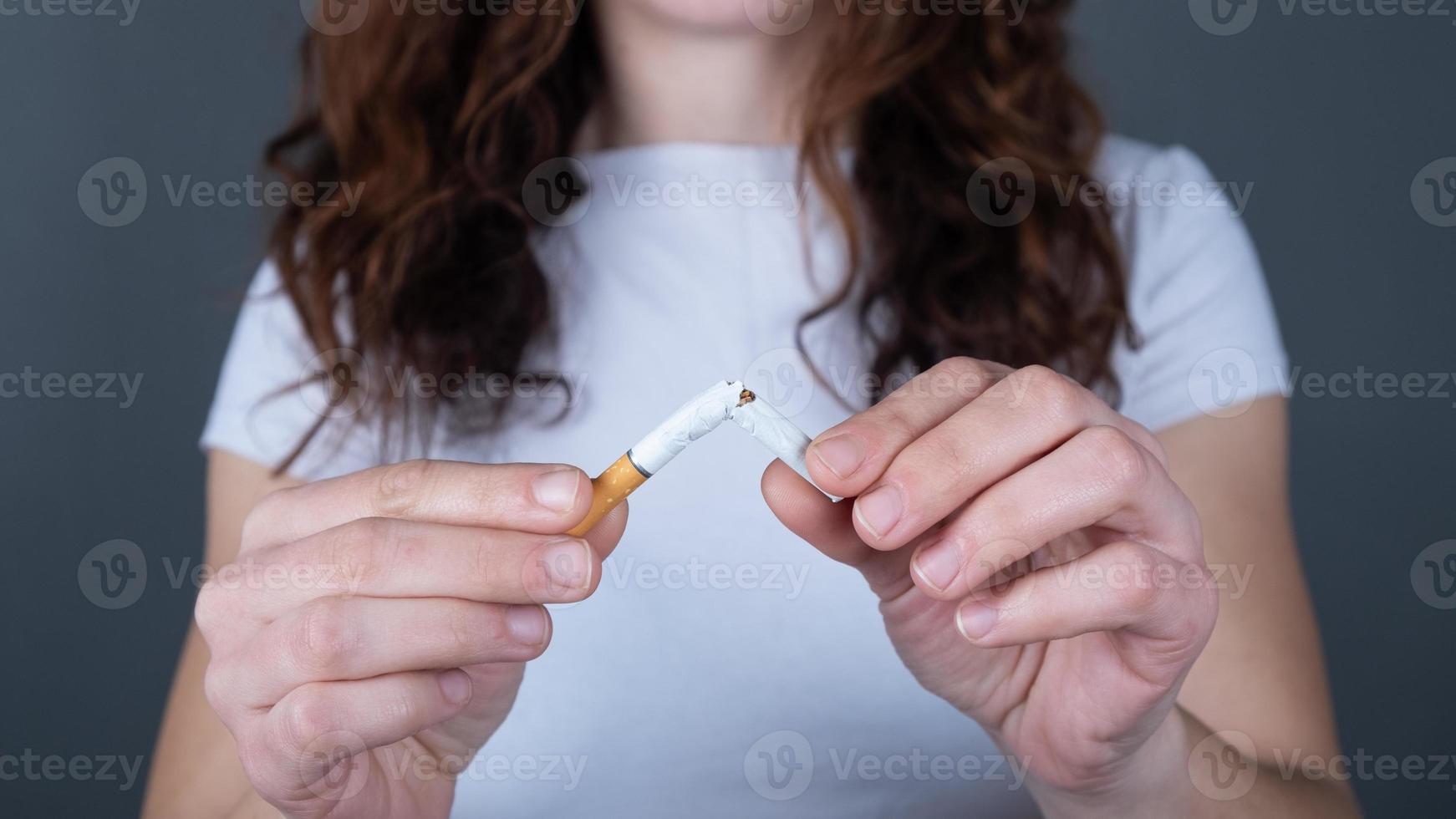 mujer sosteniendo un cigarrillo roto, dejar de fumar signo foto