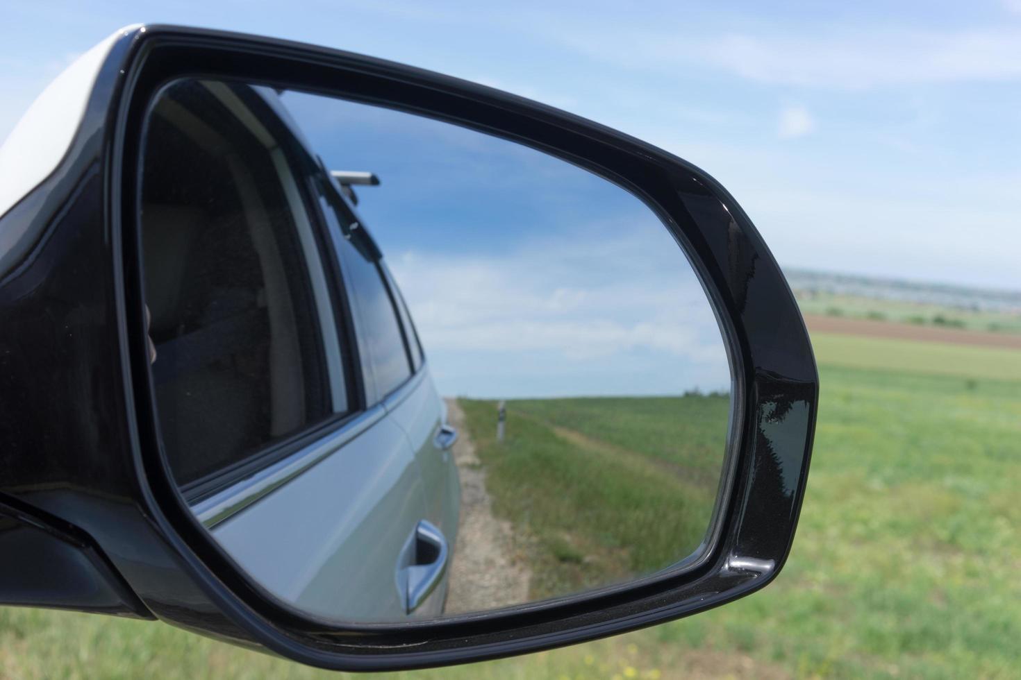 espejo de coche sobre un fondo de campos verdes. foto