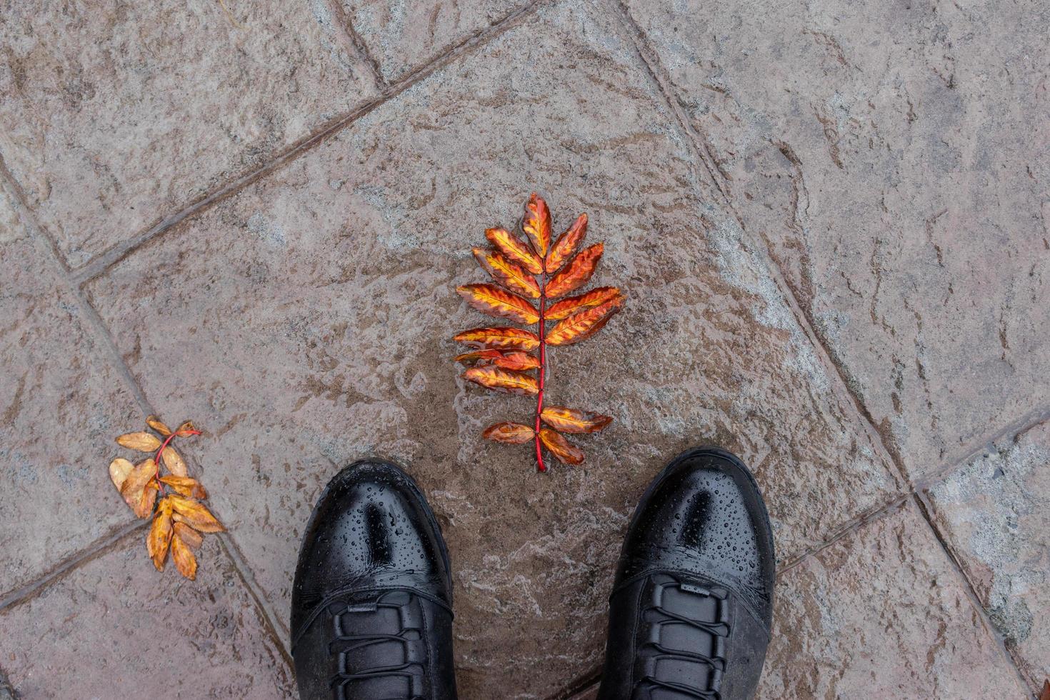 Black leather boots against the wet stone surface photo