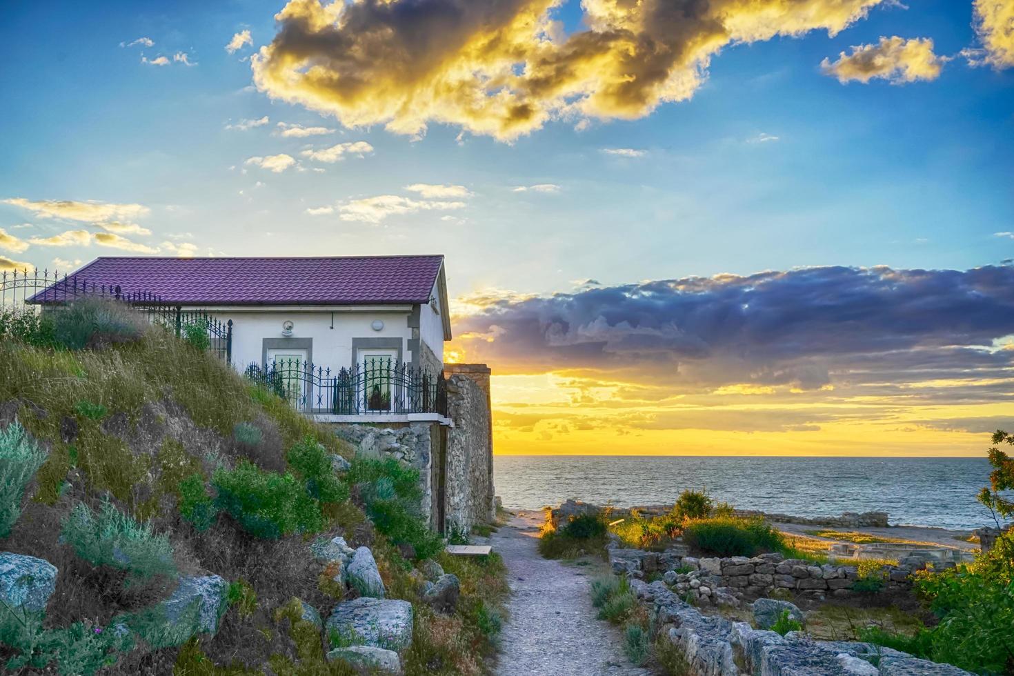 casita junto al mar durante la puesta de sol foto