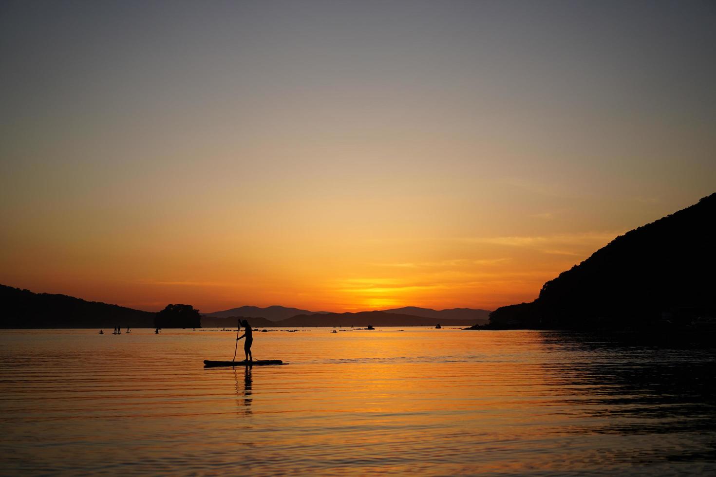 Beautiful sunset with silhouettes of people on SUP-surfer. photo