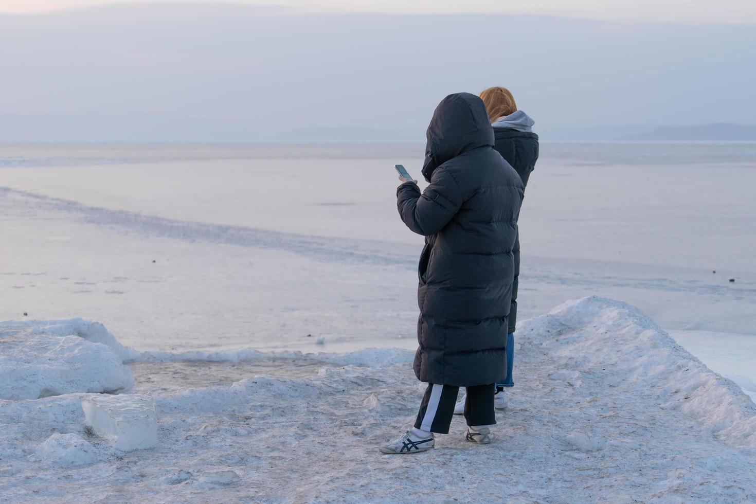 gente en ropa de invierno de pie sobre la superficie helada del mar. vladivostok. foto