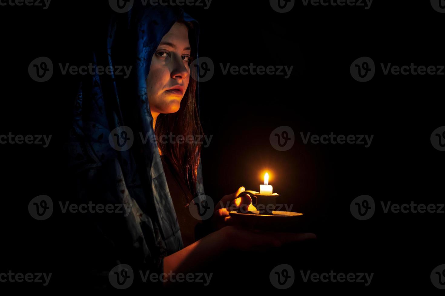 Sad young woman with candle and blue headscarf photo