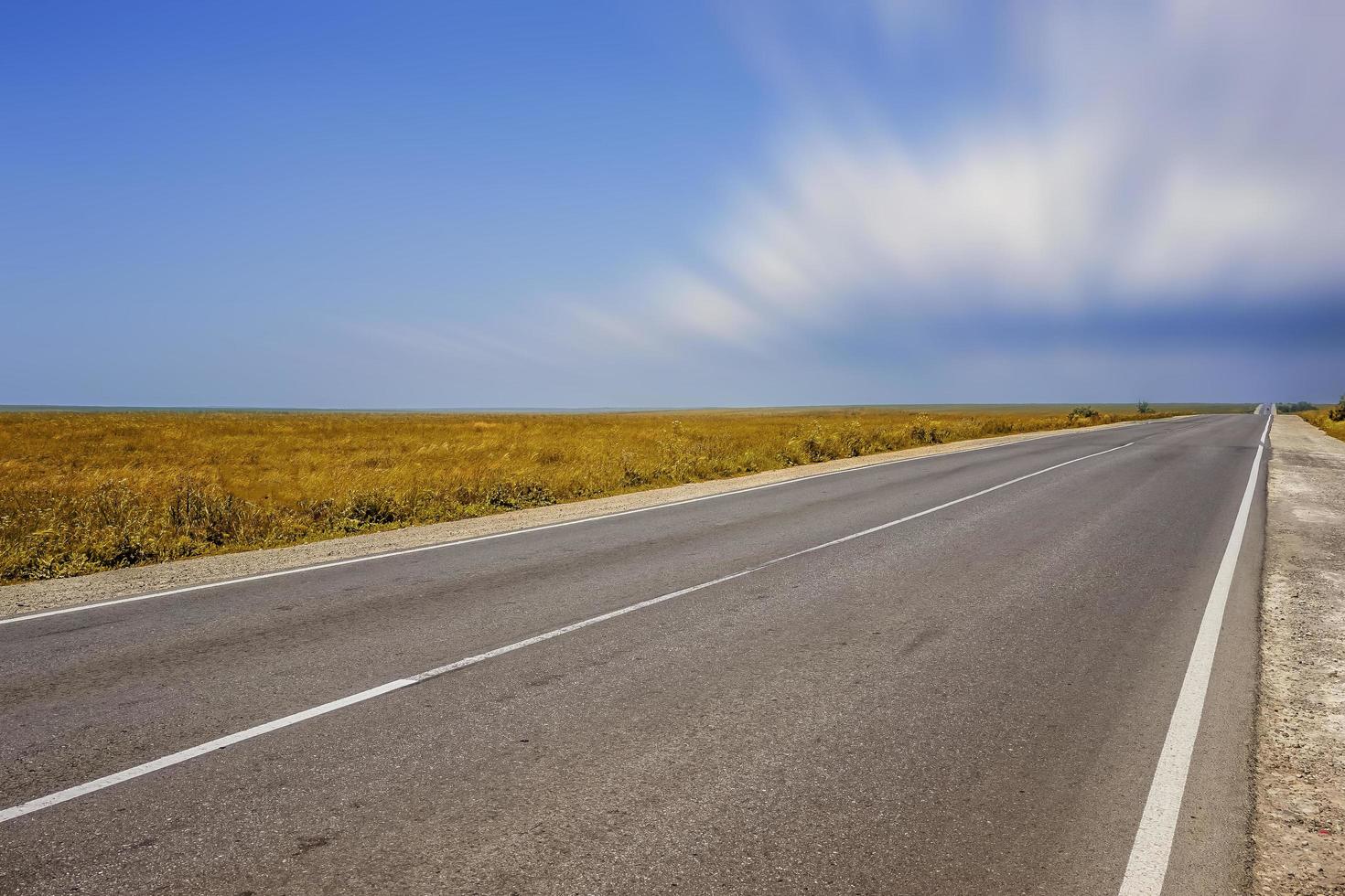 una carretera larga sin coches sobre la hierba cubierta de maleza foto