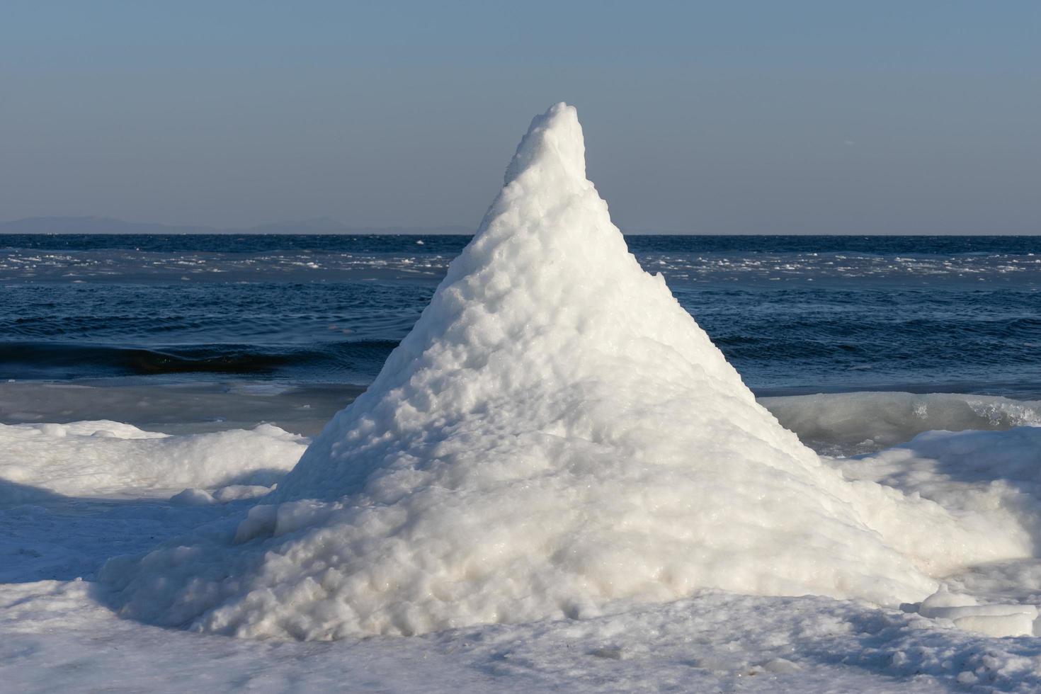 A snow pyramid on the shore of the Pacific ocean. photo