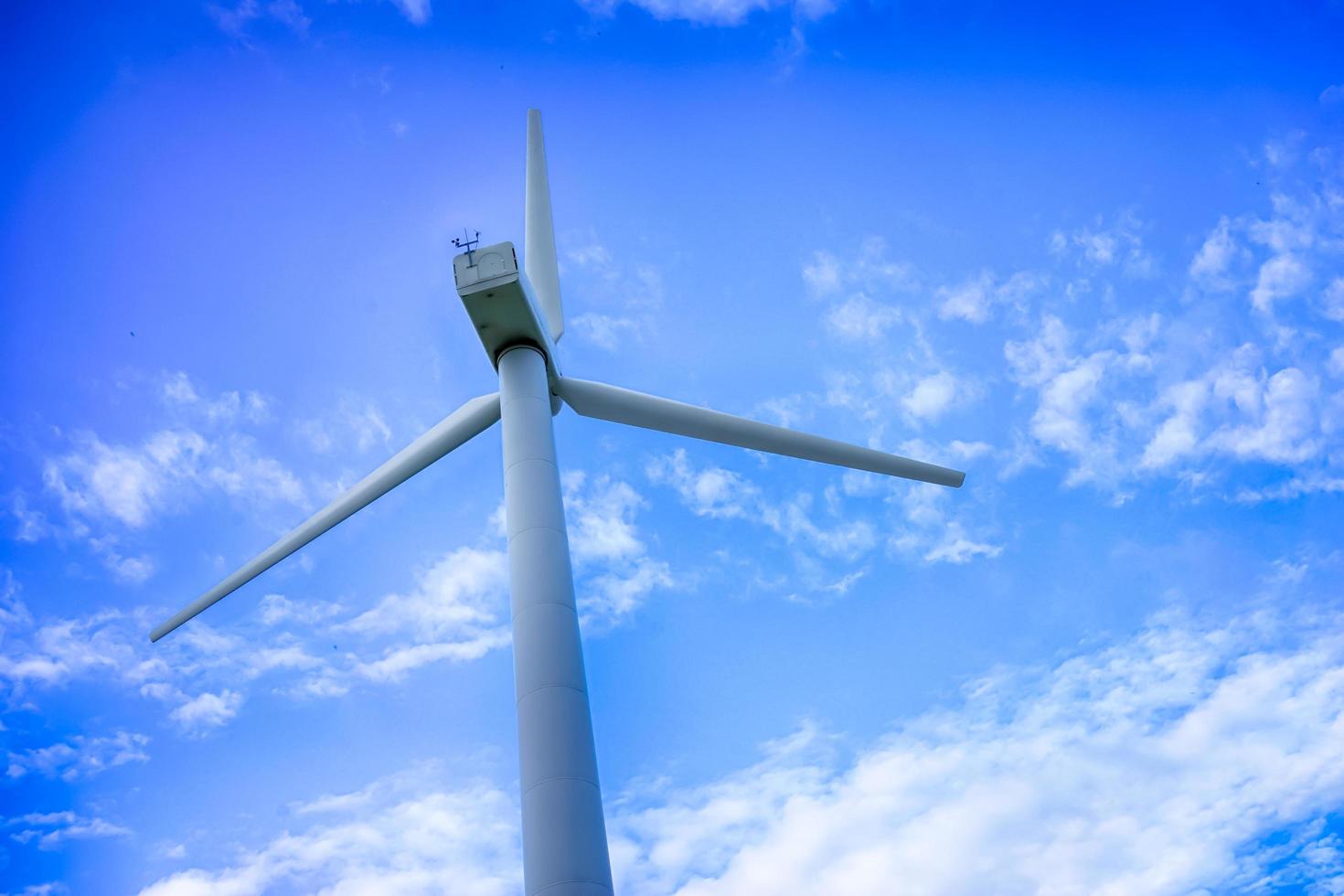 Planta de energía eólica contra un cielo azul con nubes blancas foto