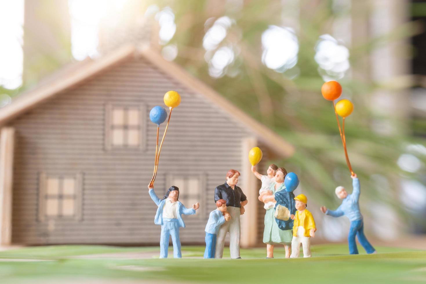 gente en miniatura, familia feliz jugando en el césped del patio trasero. concepto de vida en casa foto