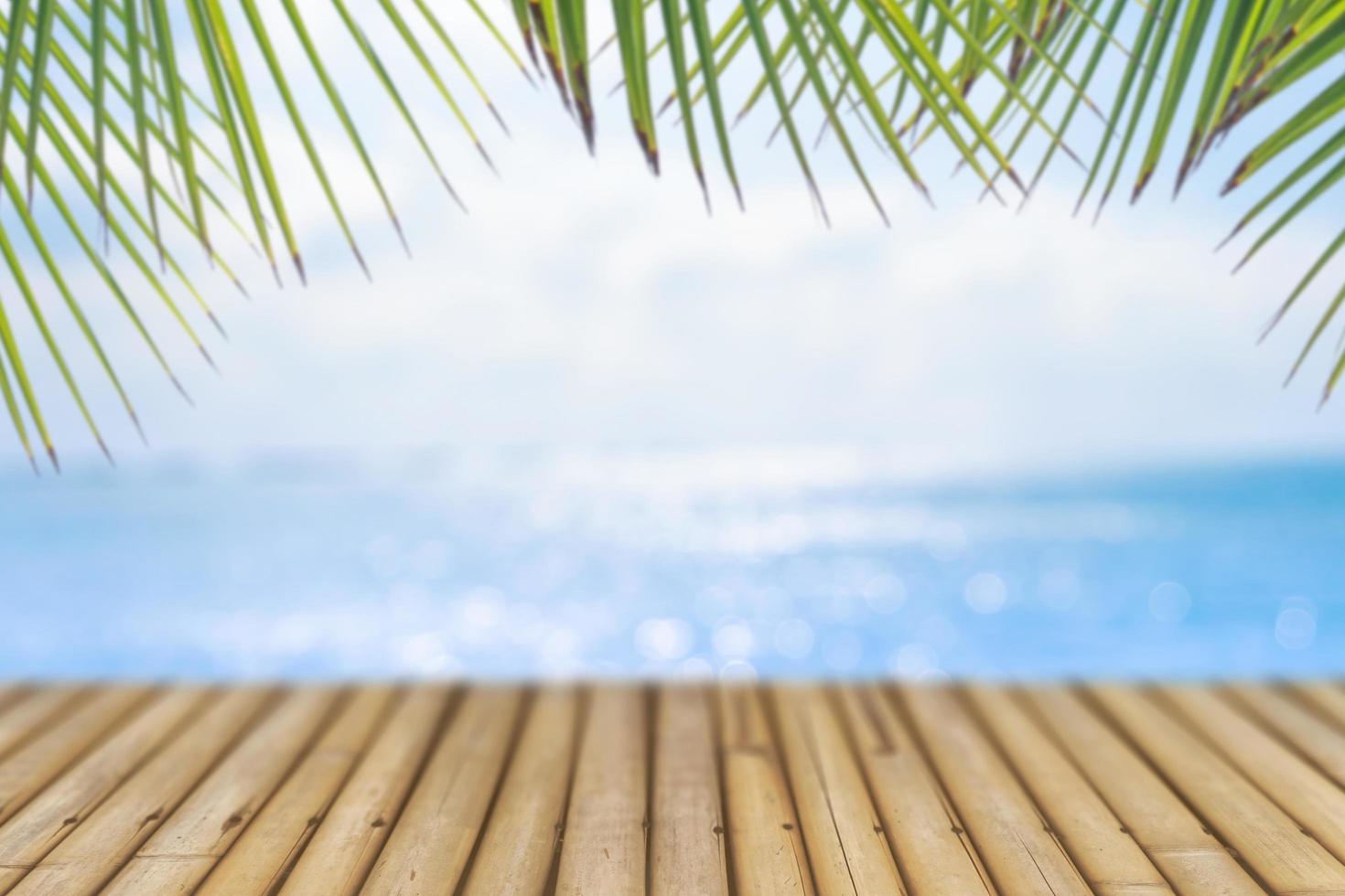 Selective focus of old wood table with a blurry beautiful beach with tropical palm trees to display your product. photo