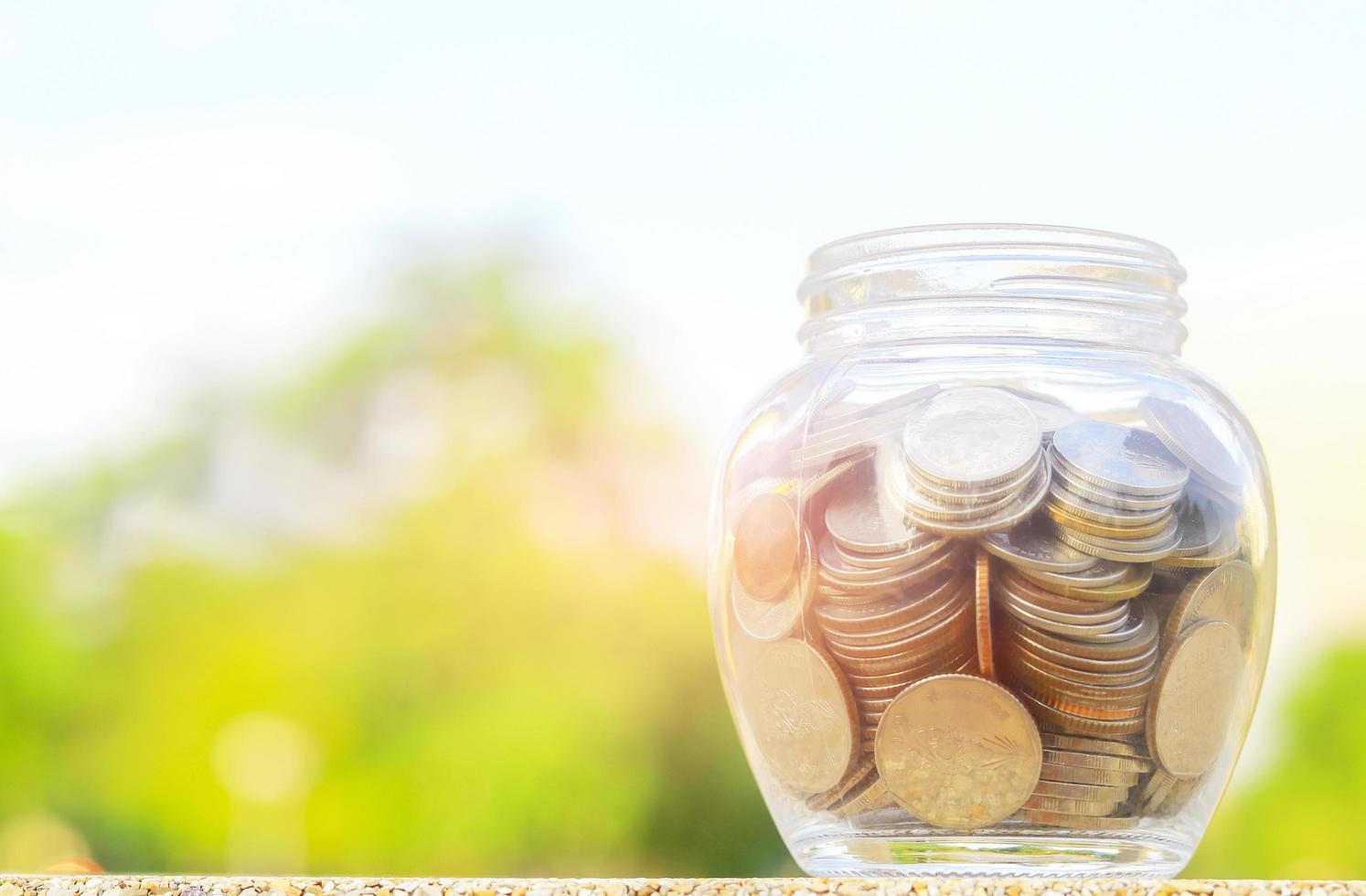 Thai coins in glass bottles on natural bokeh background. photo