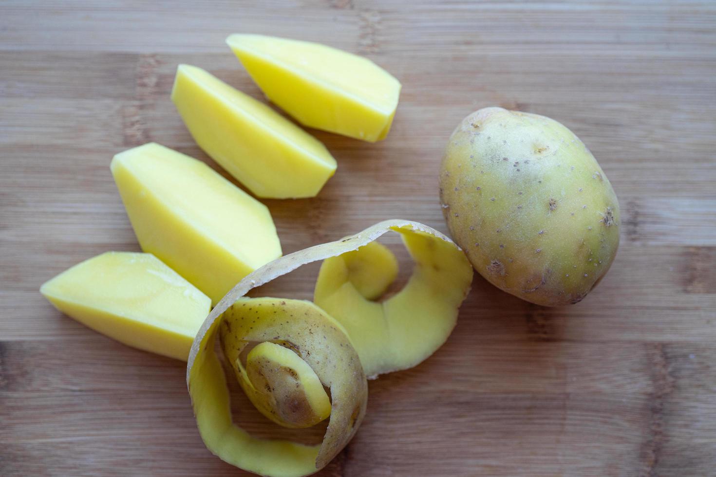 patatas crudas con cáscara sobre una tabla para cortar foto