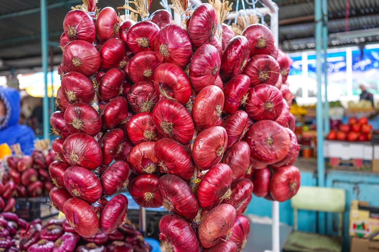 red onions in long bundles on the counter for sale. photo