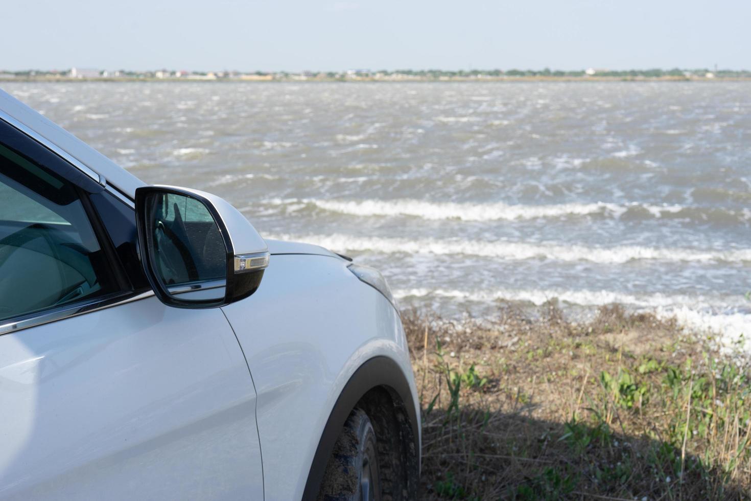 Natural landscape with a white car on the shore of a mud lake. photo