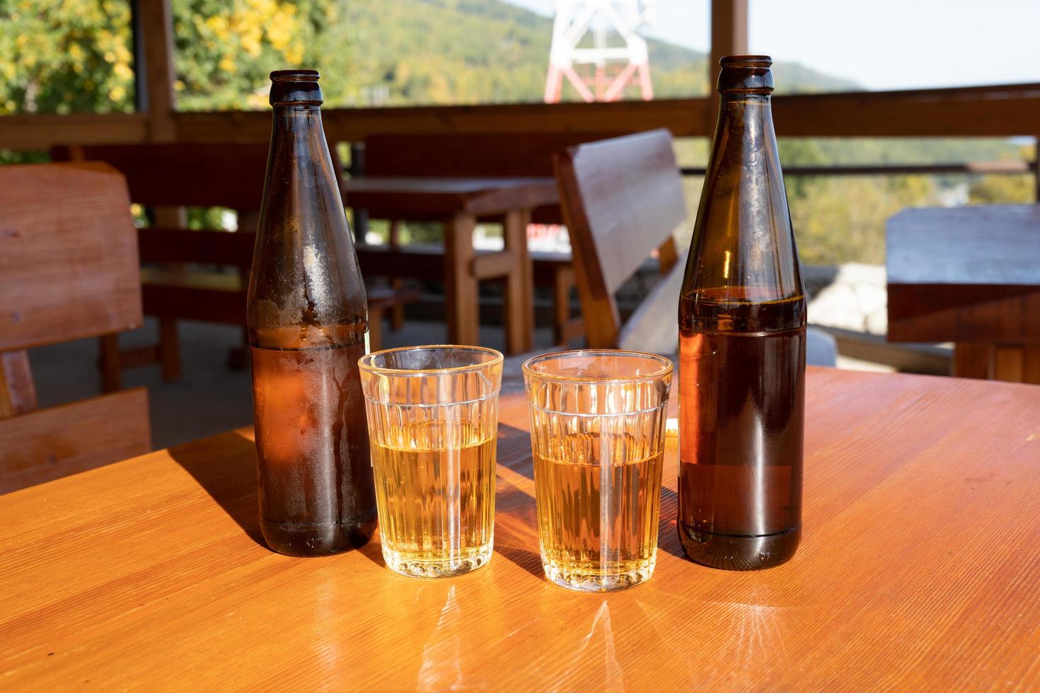 bottles and glasses with lemonade on a wooden table photo