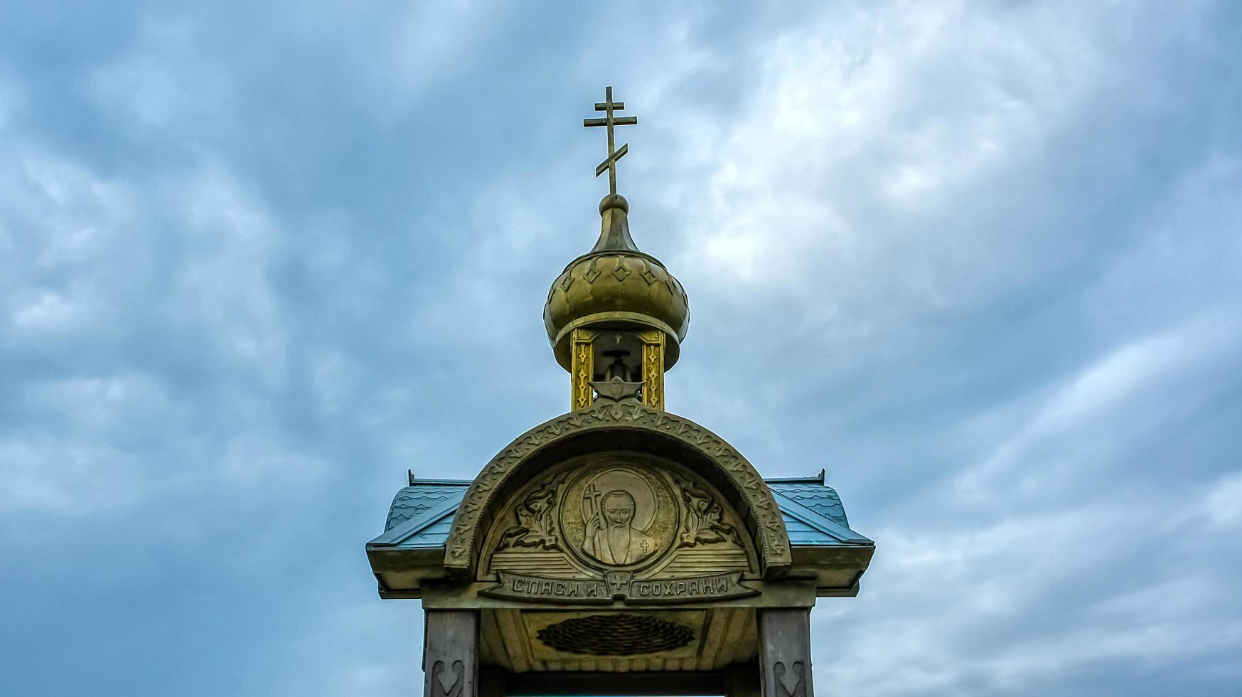 A wooden chapel on the background of cloudy sky. photo