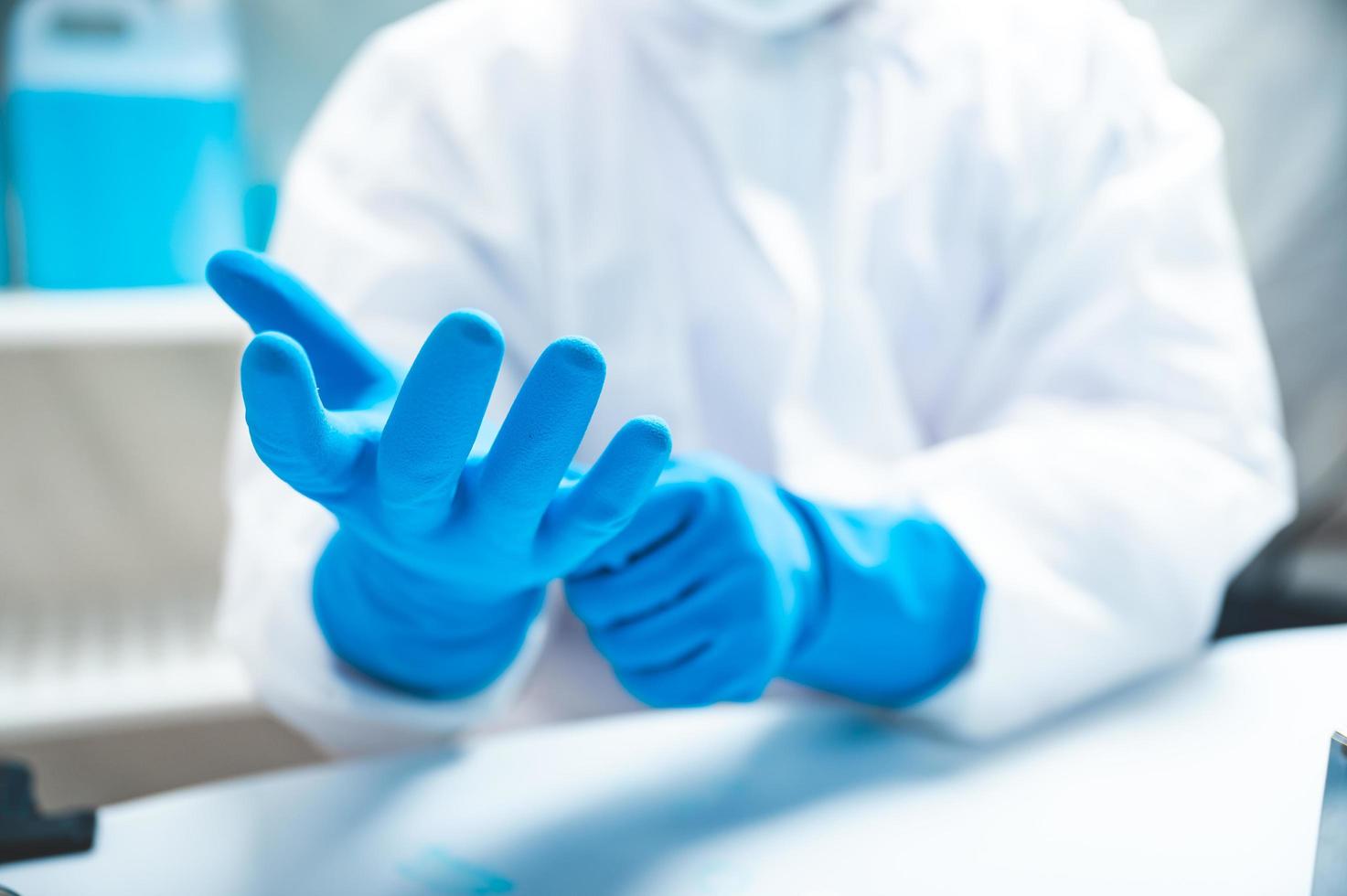 Científico o médico con guantes y máscara para trabajar en laboratorio médico, gripe epidémica de enfermedad viral, uniforme protector para la higiene, seguridad y salud en la clínica u hospital foto