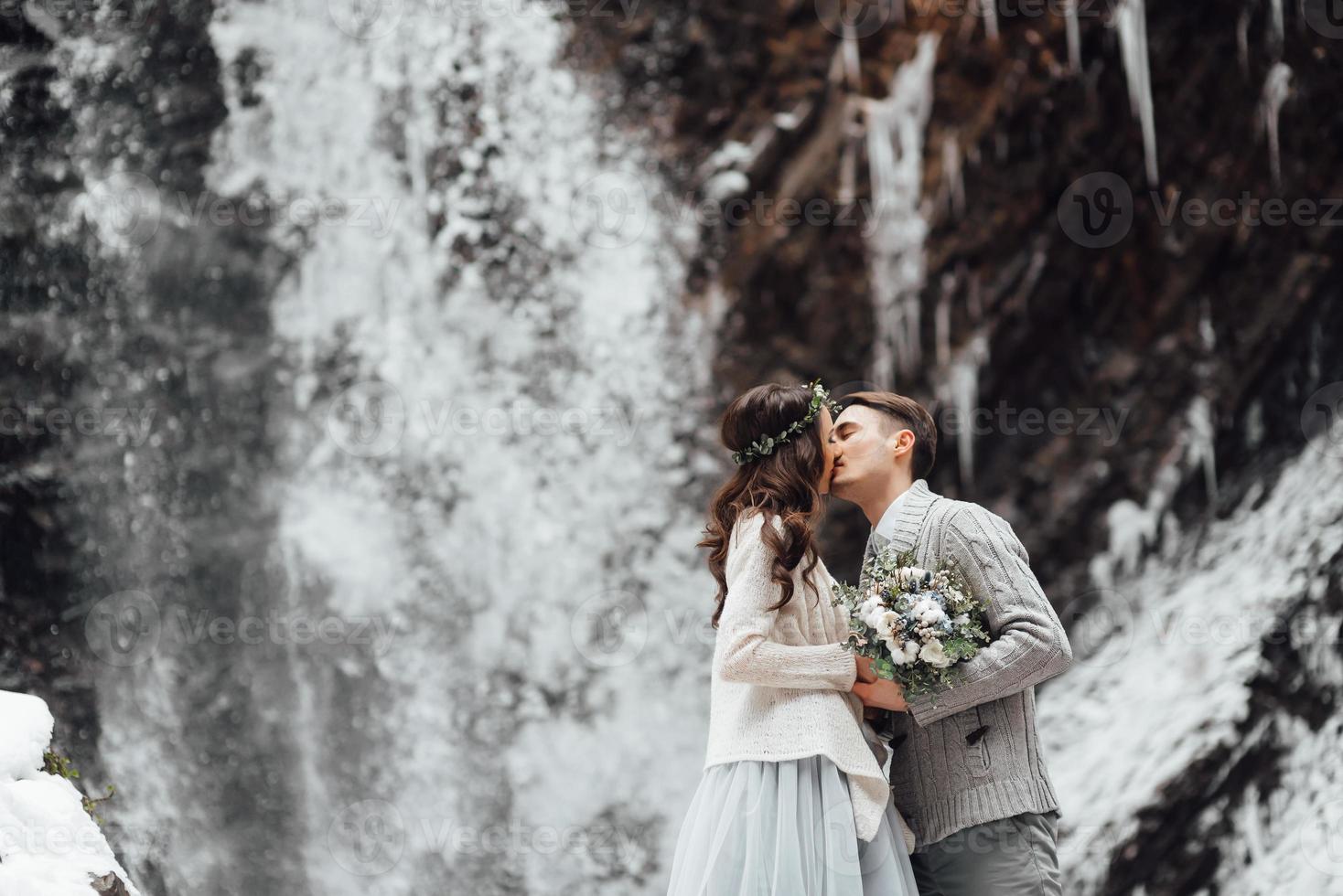 novios en la cascada de la montaña foto