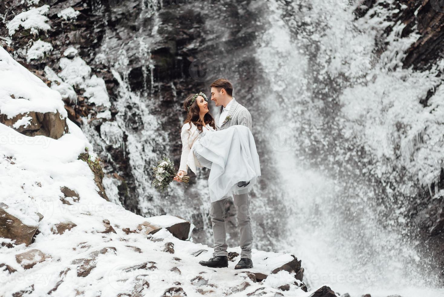 novios en la cascada de la montaña foto