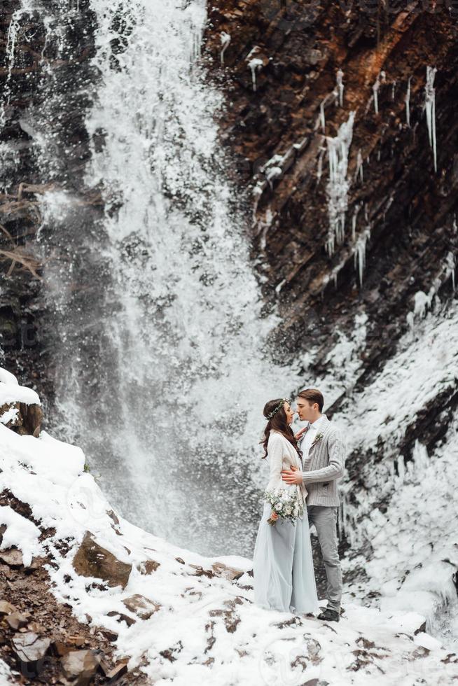 novios en la cascada de la montaña foto