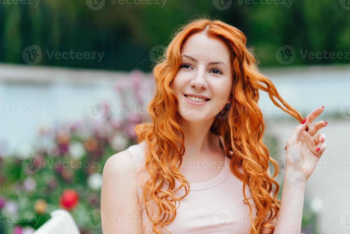 Red-haired young girl walking in a park between trees and architectural objects photo