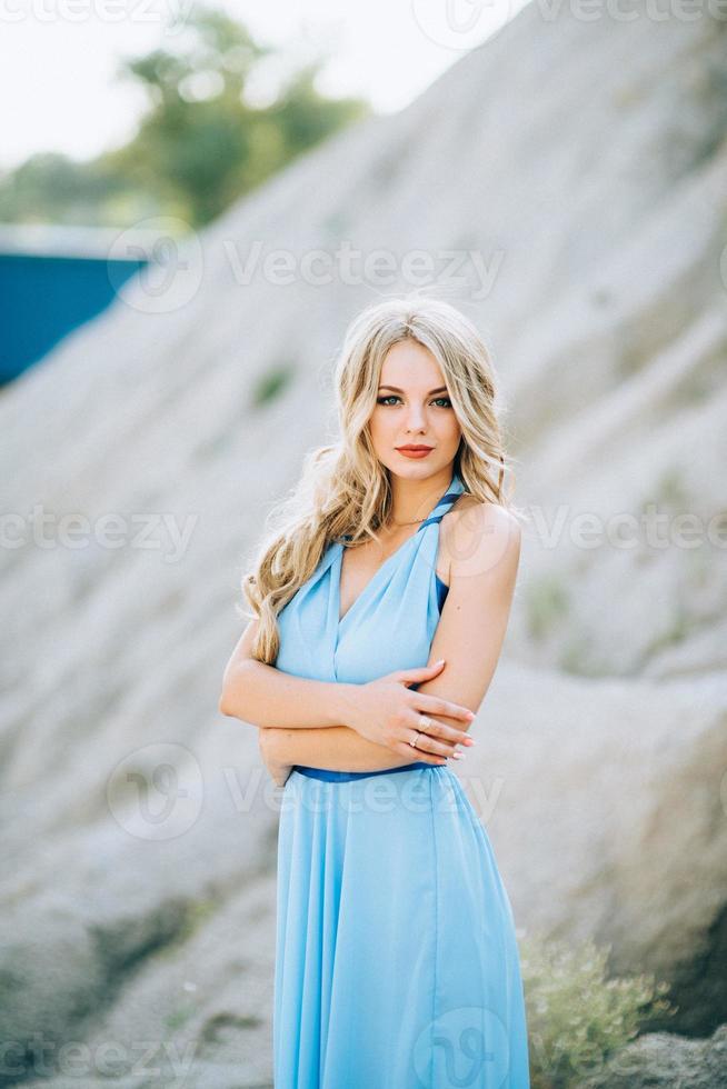 Chica rubia con un vestido azul claro en una cantera de granito foto